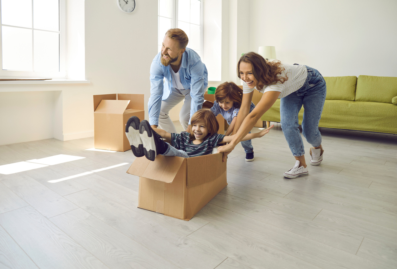 Happy Young Parents and Children Playing with Cardboard Boxes in Their New Apartment